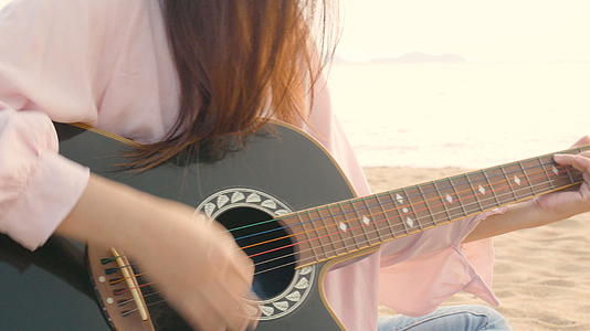 长发女郎在沙滩上弹奏吉他视频的预览图