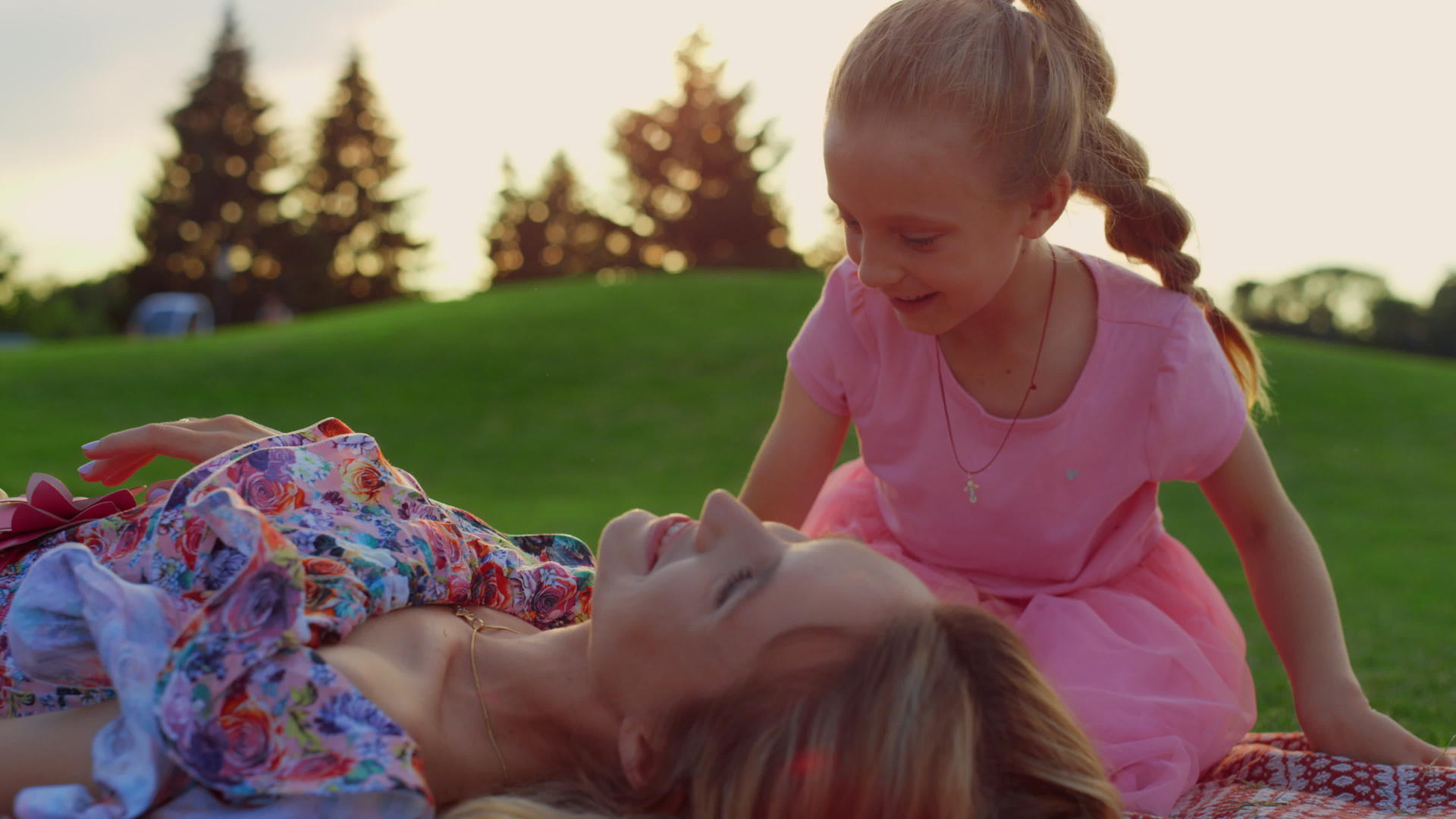 女孩在绿草地上亲吻女人母亲和儿子在城市公园里玩耍视频的预览图