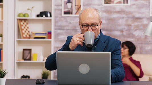 老人用笔记本电脑工作时享受一杯咖啡视频的预览图