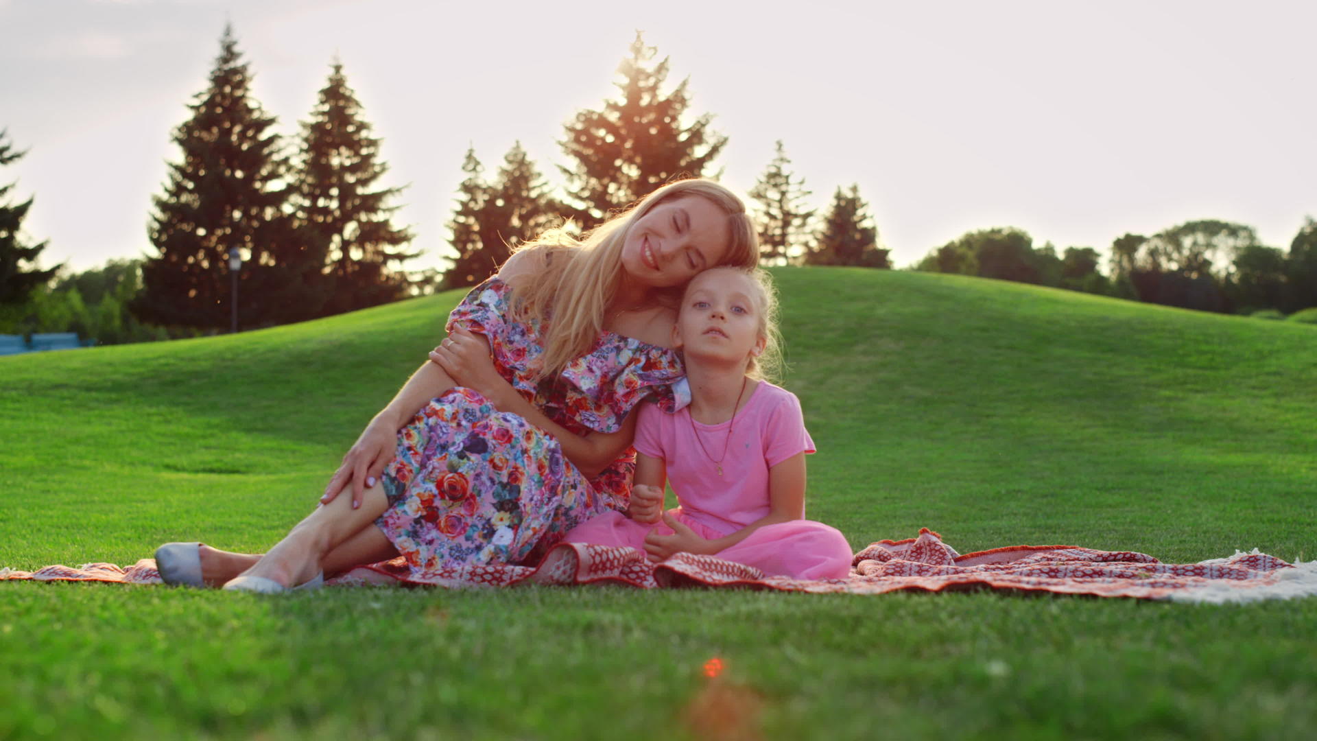 日落时家庭在草地上摆姿势女人在城市公园拥抱女孩视频的预览图