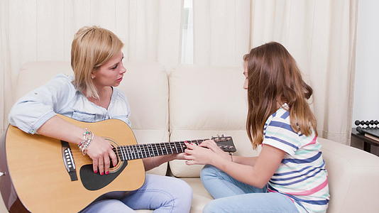 女儿向母亲展示了如何在吉他上演奏一首歌视频的预览图