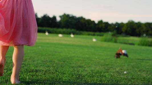 女孩穿着粉红色的裙子在公园里赤脚走路视频的预览图