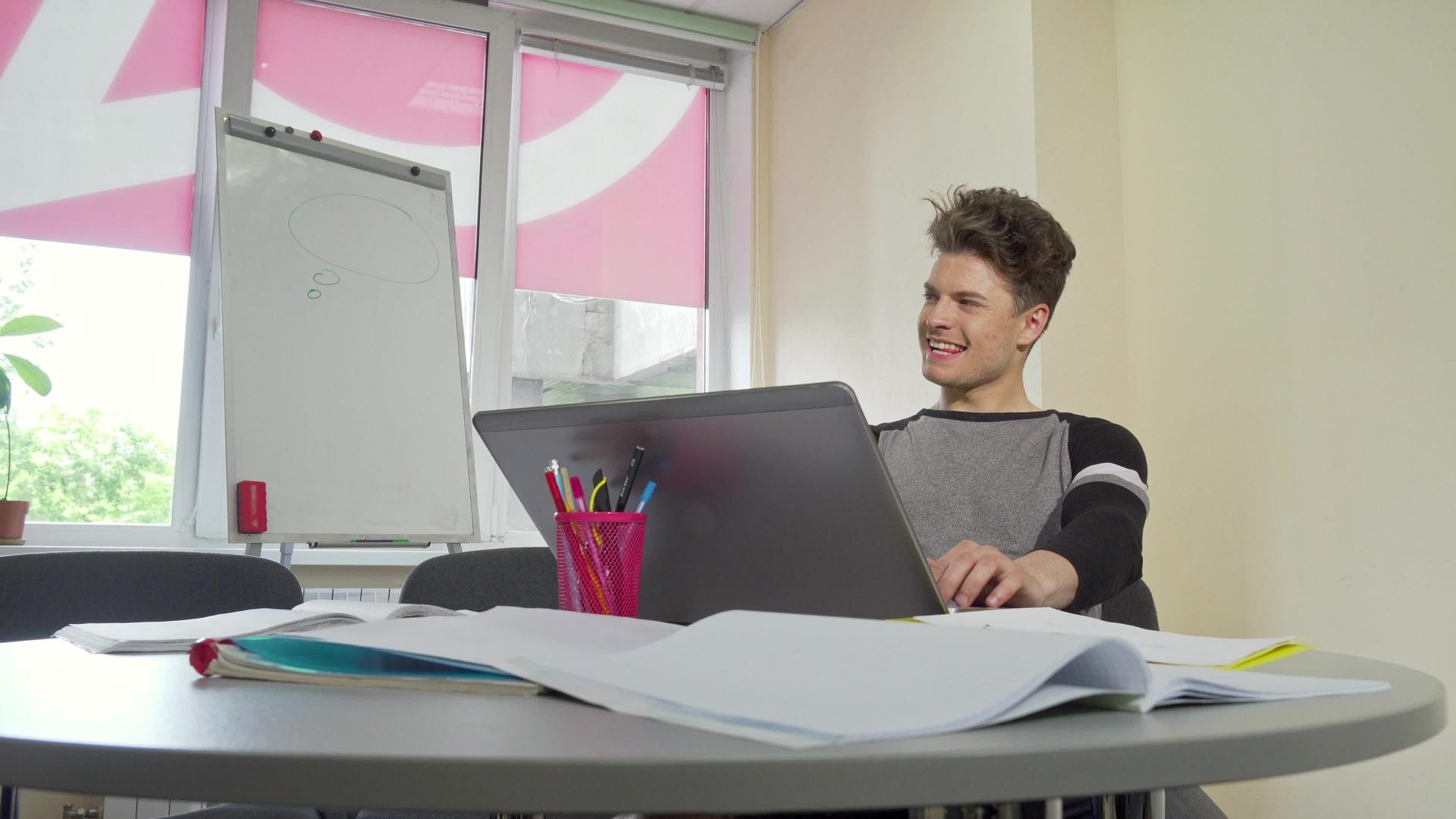 年轻的男大学生微笑着打开笔记本电脑视频的预览图