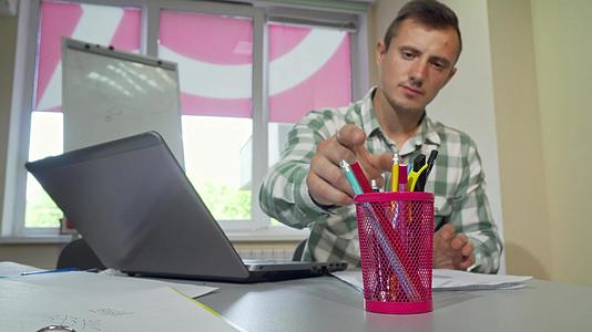 年轻人在大学图书馆学习从前面的杯架上拿铅笔视频的预览图