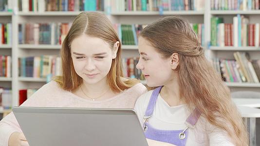 两个女孩在图书馆学习享受一起学习的快乐视频的预览图