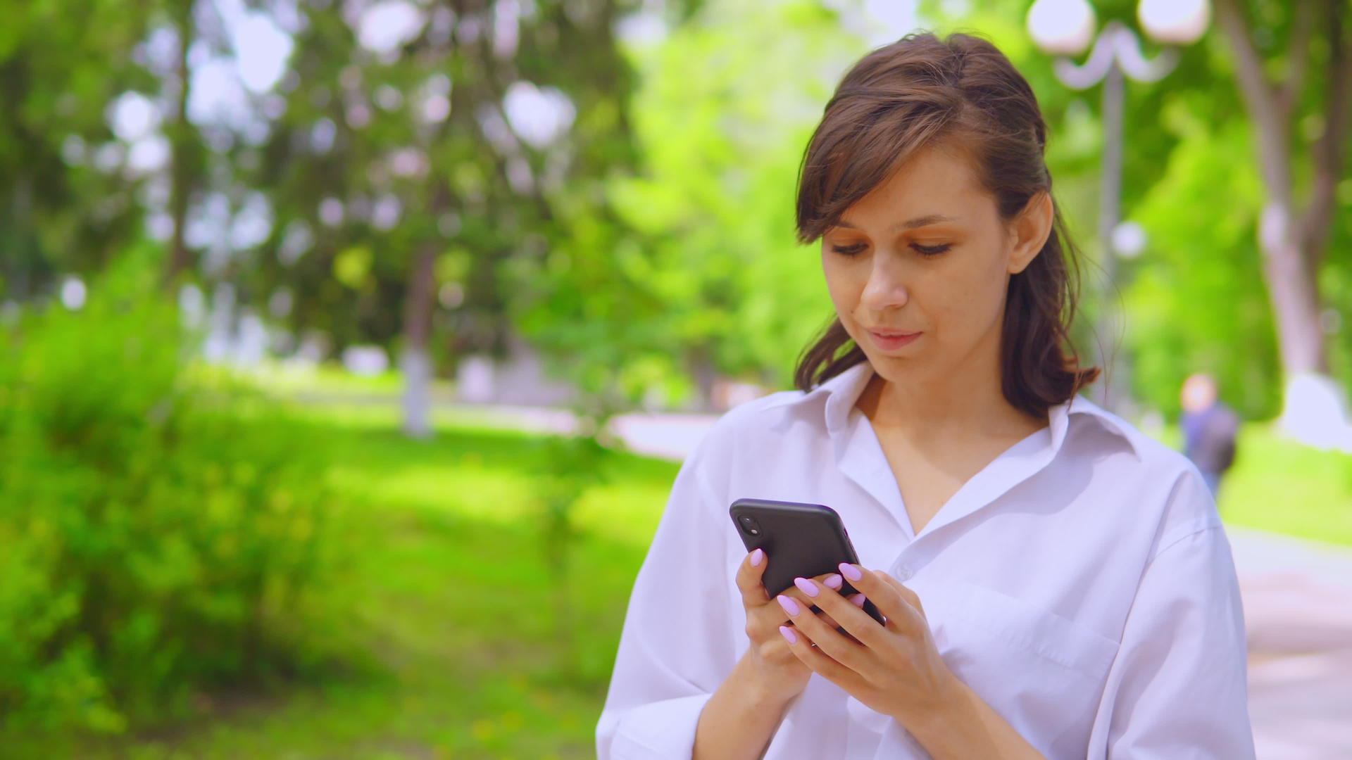 在公园里用手机在网上聊天的年轻女商人视频的预览图