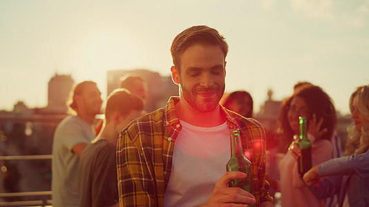 快乐的男人在日落的屋顶上喝啤酒视频的预览图
