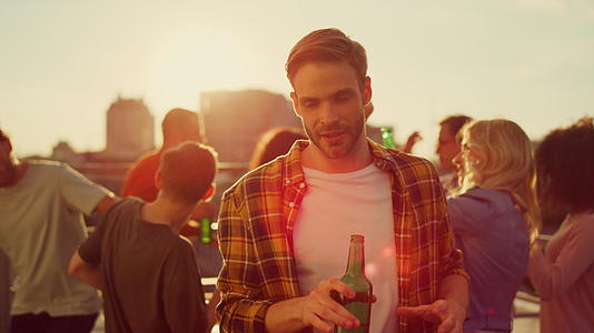 帅哥在聚会上喝一瓶啤酒放松视频的预览图