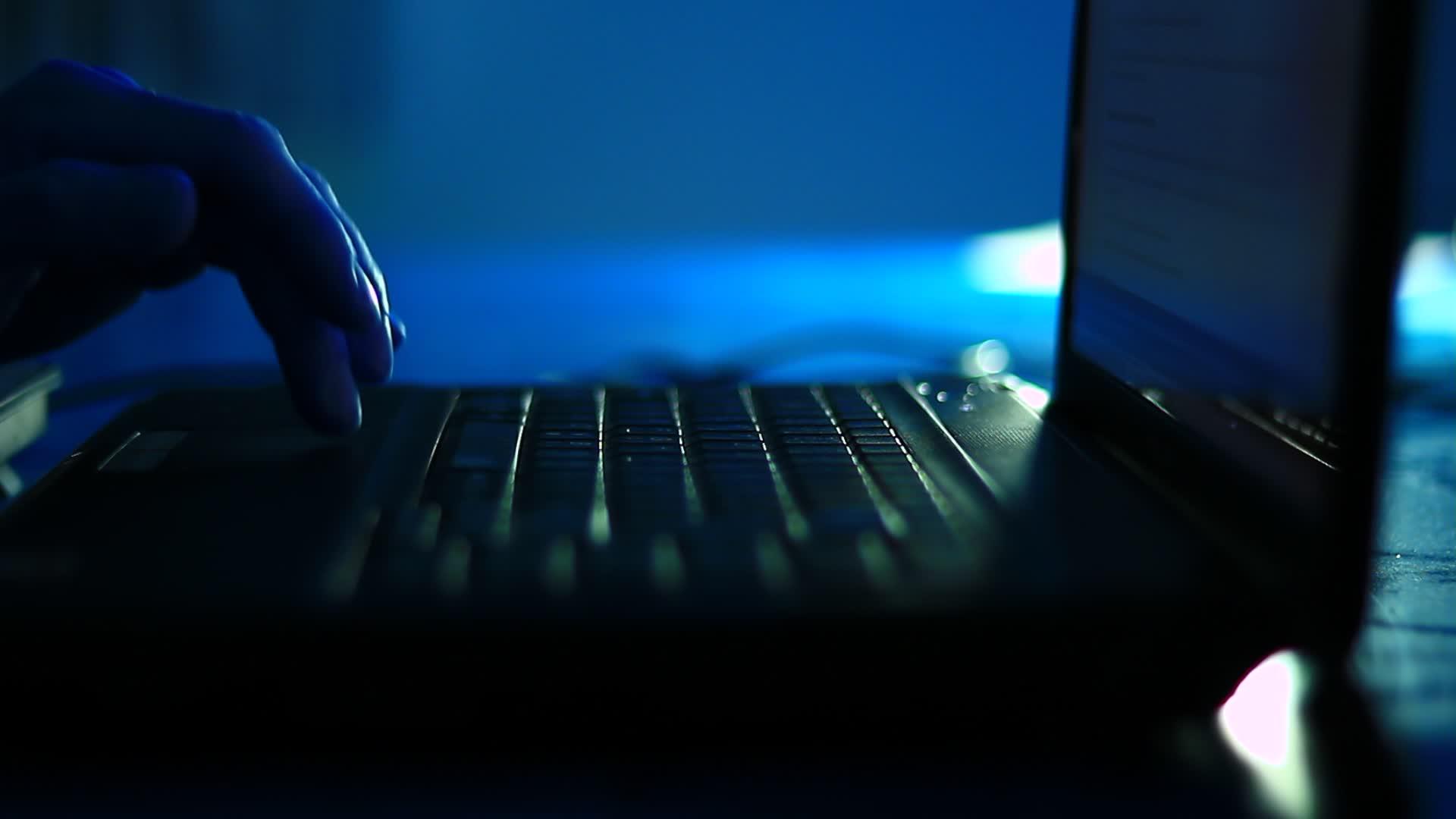 不知名的男人在黑暗中使用笔记本电脑视频的预览图