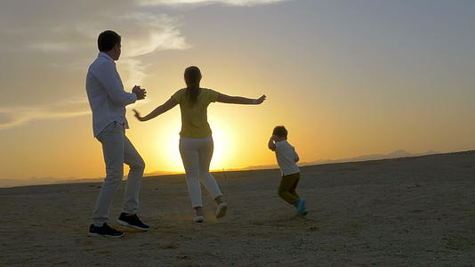 日落时在海滩上跳舞的三个幸福家庭视频的预览图