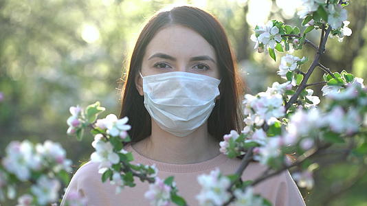 春天苹果花里戴着医用面具的女人视频的预览图