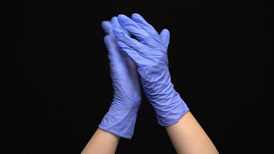 用蓝色手套拍打黑色背景的医用手视频的预览图