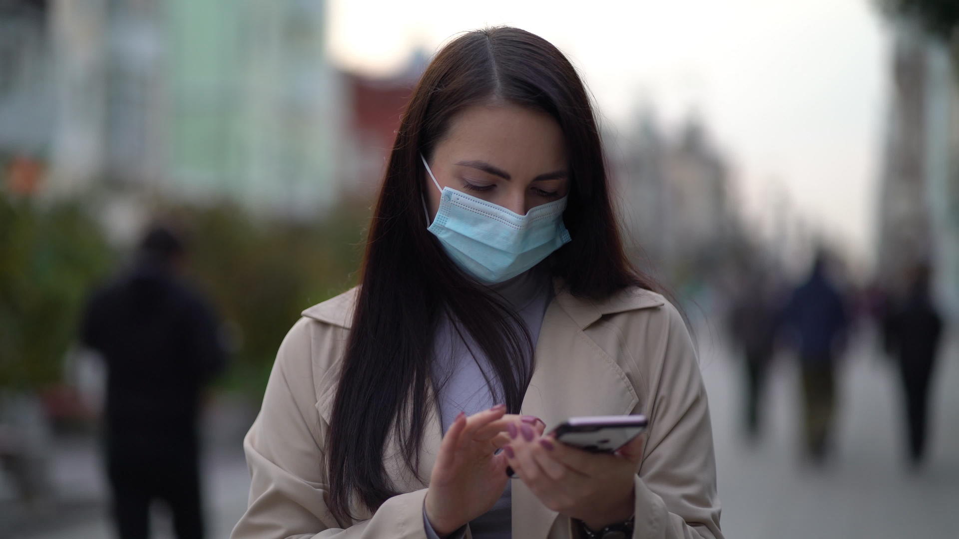 戴着防护医用口罩的肖像女走上街用电话短信卷轴走上街视频的预览图