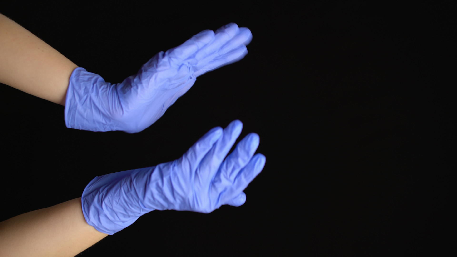 带有蓝色手套的垂直视频医疗手在黑色背景上鼓掌视频的预览图