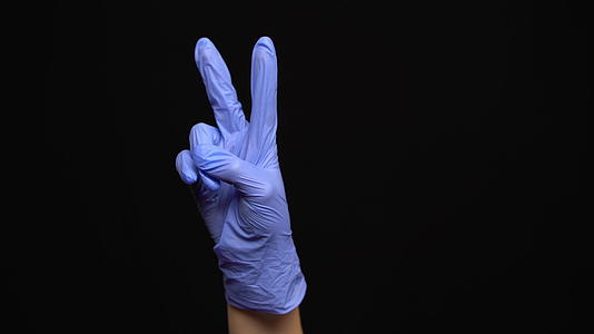 女性用乳胶戴的医用手套做出和平的姿势孤立黑色背景视频的预览图