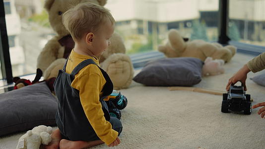 可爱的兄弟坐在家里的地毯上玩玩具卡丁车视频的预览图