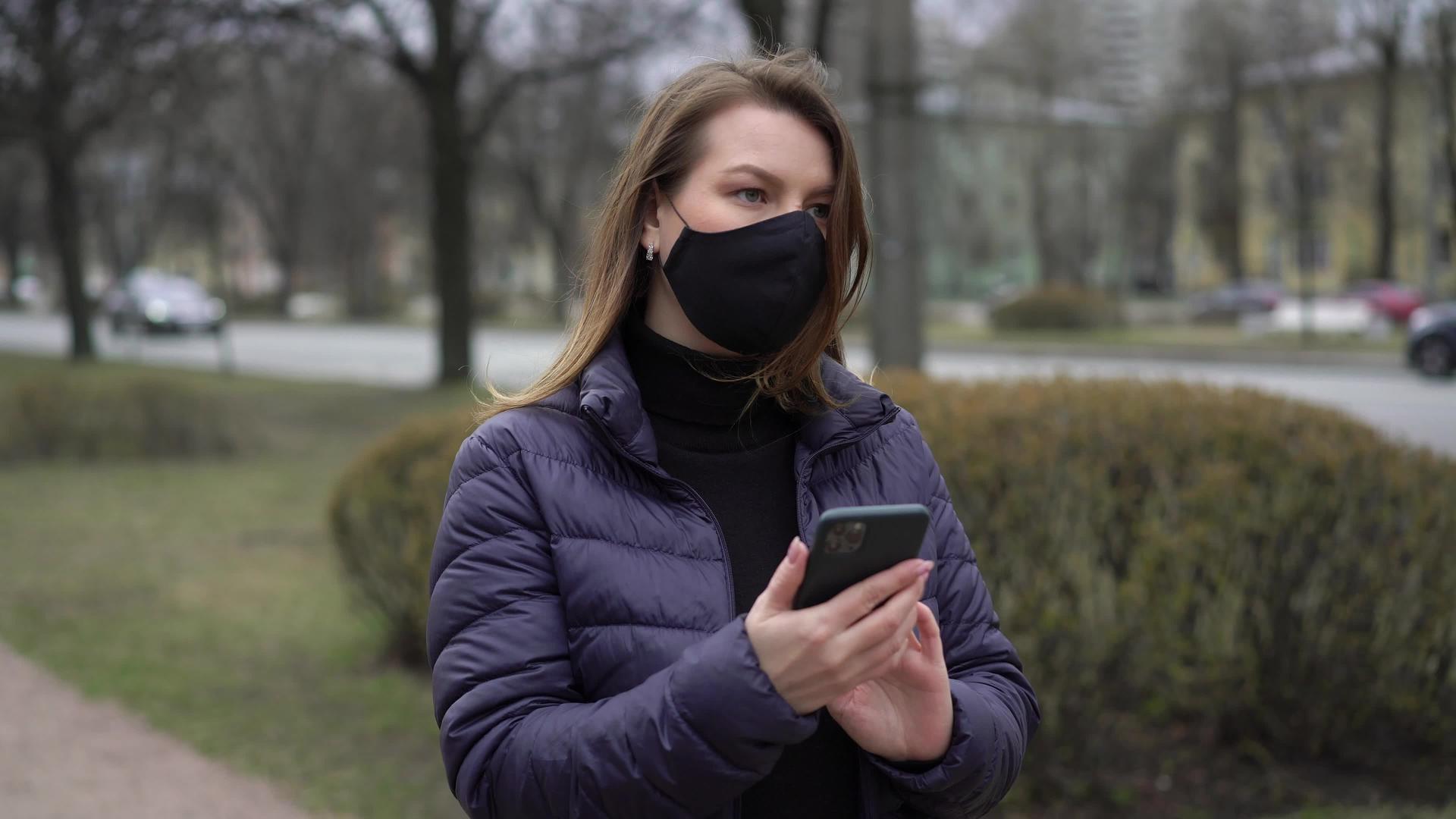 在有手机的城市妇女戴着保护性口罩视频的预览图