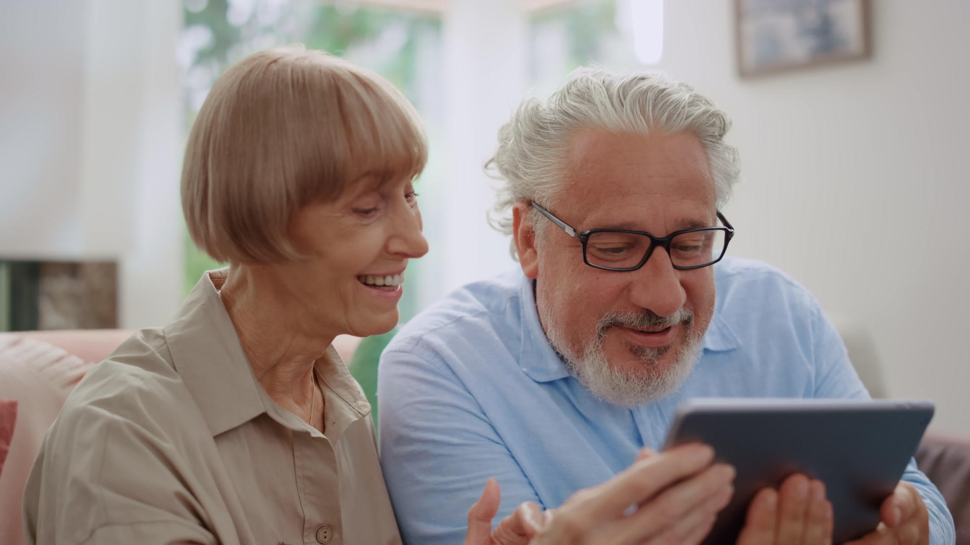 祖母和祖父在平板电脑上通过视频电话与孙子孙女交谈视频的预览图