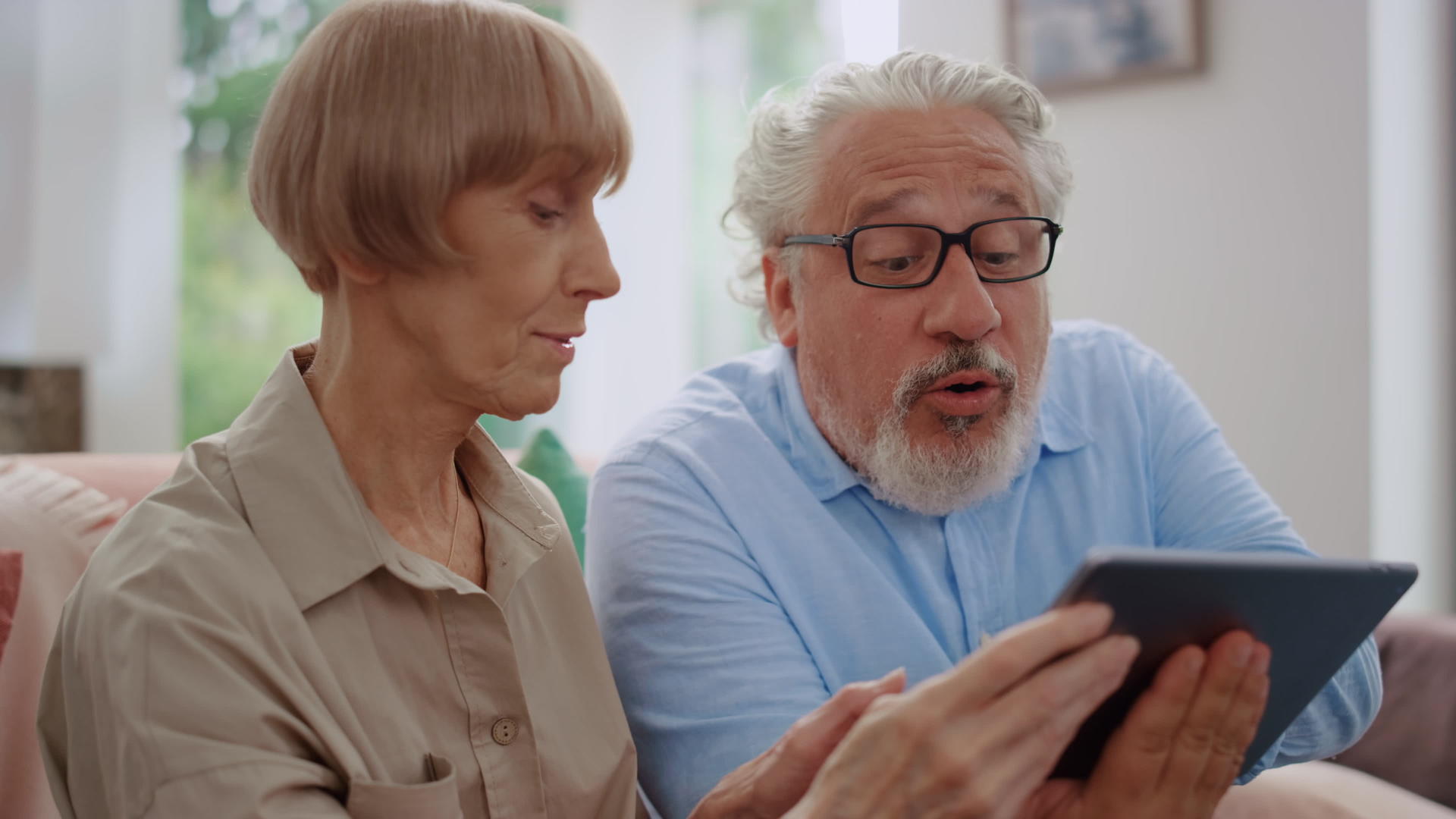 祖父和祖母使用平板电脑进行视频通话观看平板电脑屏幕上的男子视频的预览图