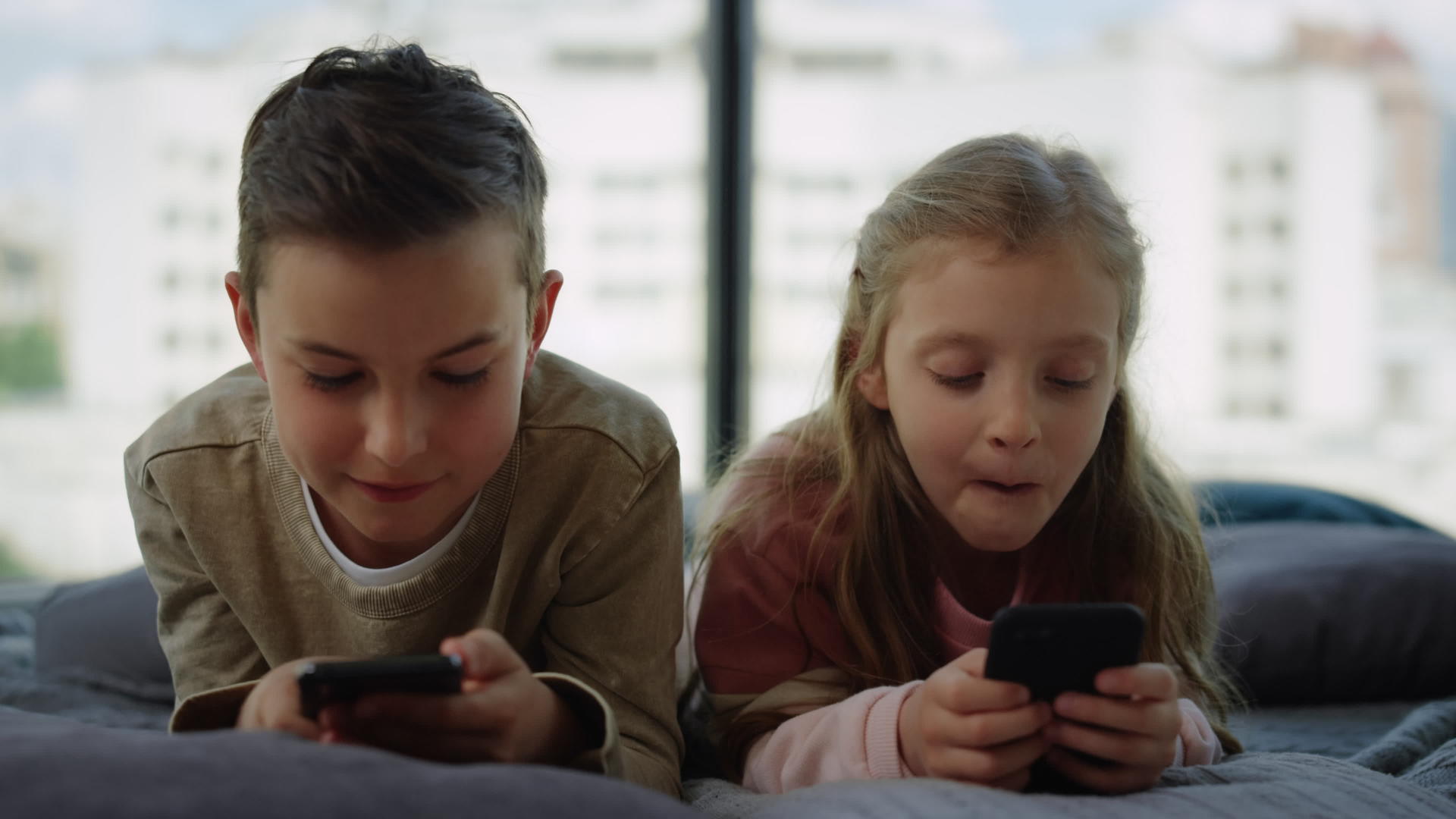 哥哥和姐姐在手机上玩游戏小弟弟在家玩智能手机视频的预览图