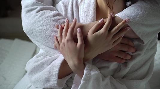 年轻夫妇穿着浴袍坐在床上拥抱握手视频的预览图
