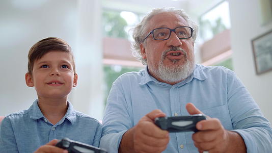 快乐的孙子和爷爷在客厅里玩电子游戏视频的预览图