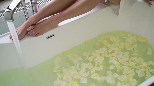 女人坐在浴缸的浴室里用花瓣洗澡视频的预览图