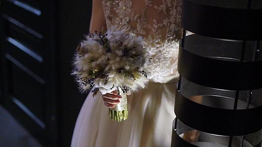 穿着结婚礼服的年轻新娘在室内盛开花束和白色豪华礼服视频的预览图