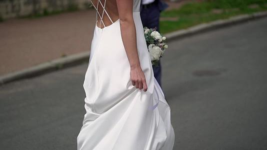 穿着婚纱的年轻新娘在城市里穿着白色豪华服装视频的预览图