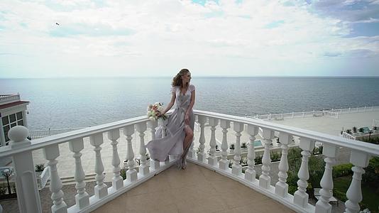 露台上穿着内衣的年轻金发女子穿着海上新娘花束视频的预览图
