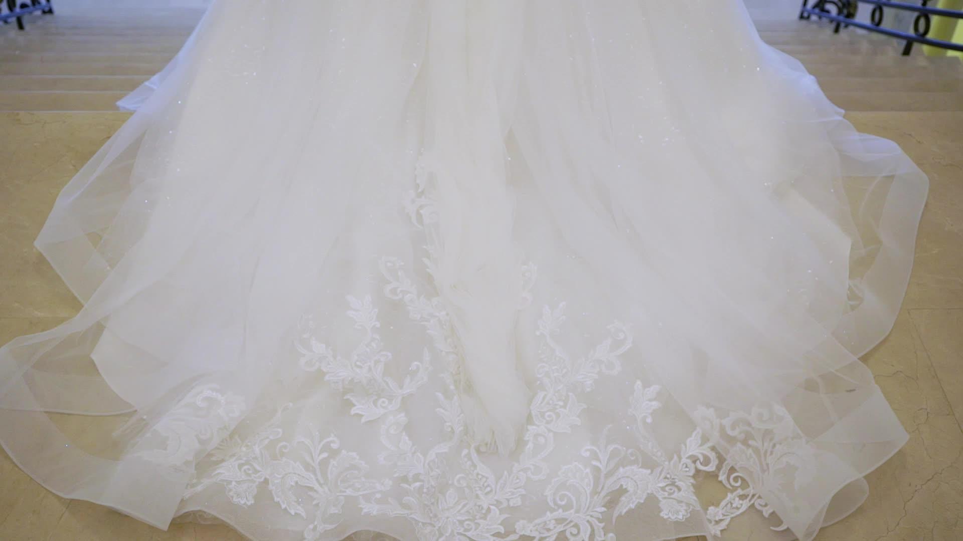年轻的新娘穿着白色婚纱从楼梯上下来视频的预览图