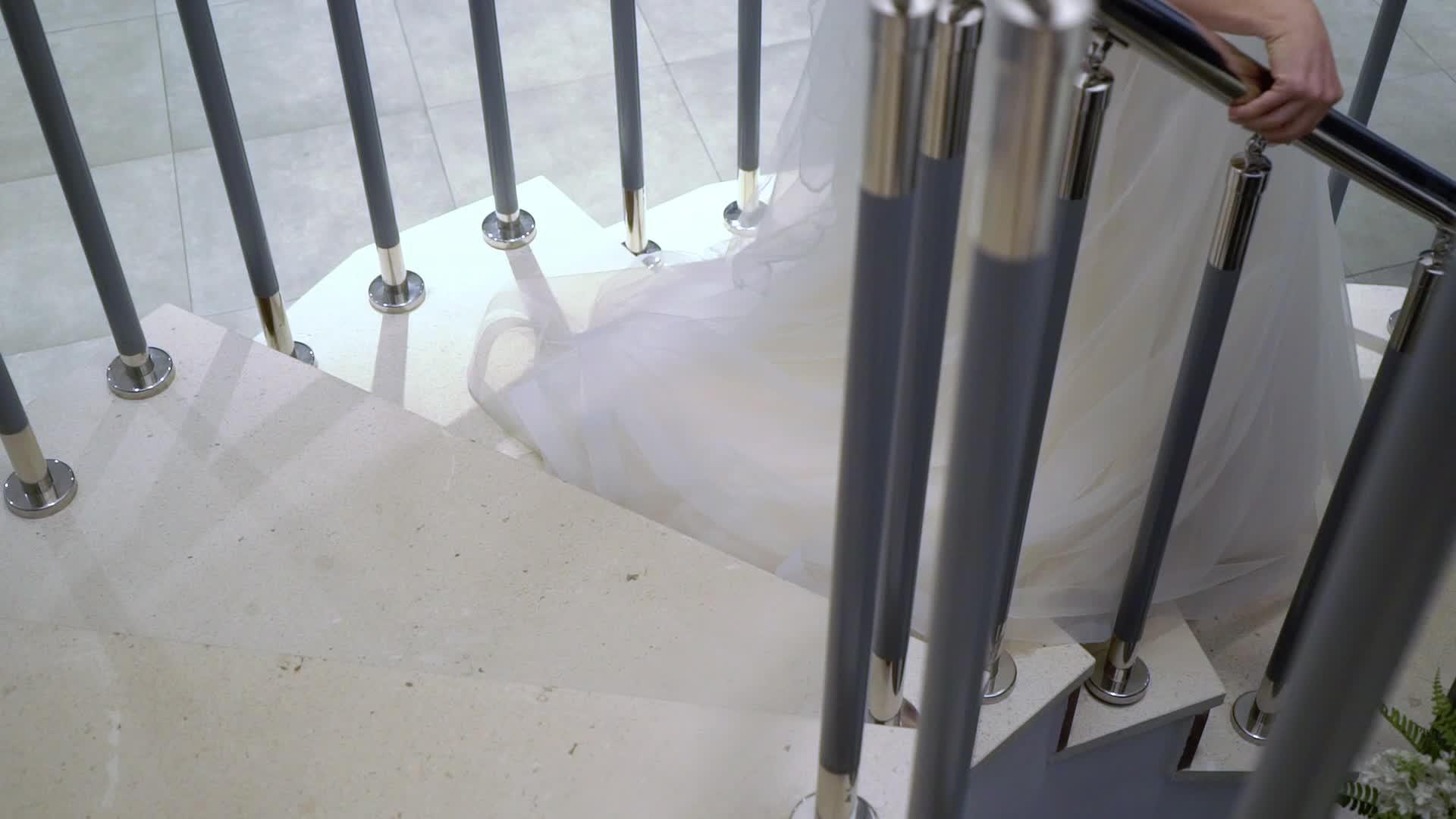 年轻的新娘穿着白色婚纱从楼梯上下来视频的预览图