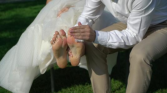 婚礼当天男子赤脚走路后从草地上打扫女孩的脚视频的预览图