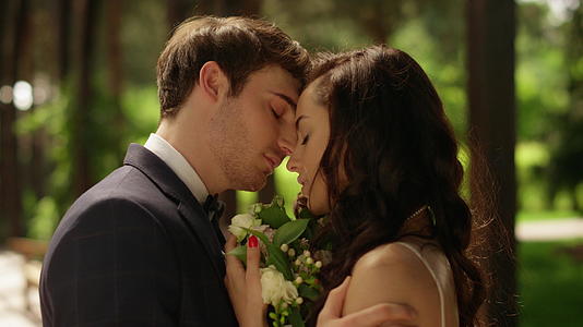 深情的男人在户外亲吻女人的前额花园里的情侣摆姿势视频的预览图