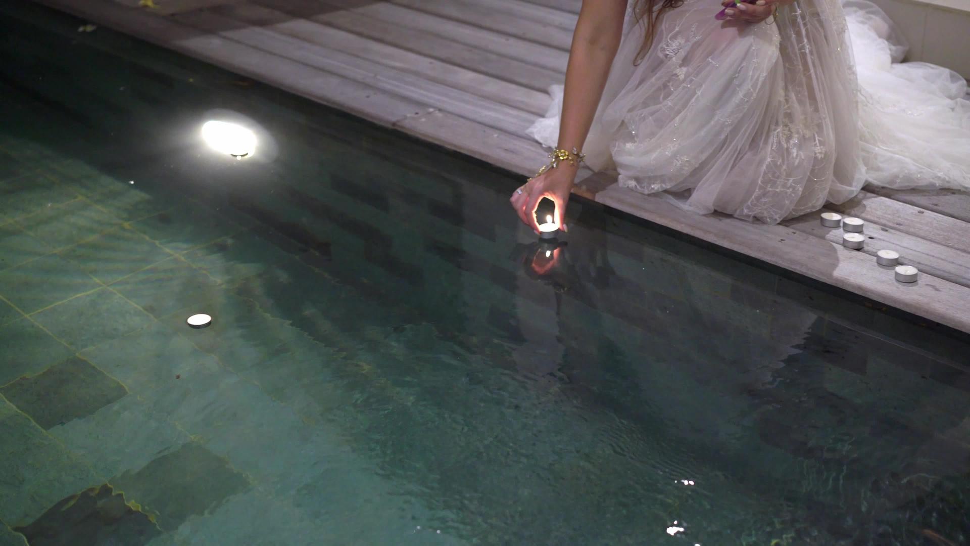 晚上年轻美丽的新娘在别墅游泳池附近带着蜡烛视频的预览图