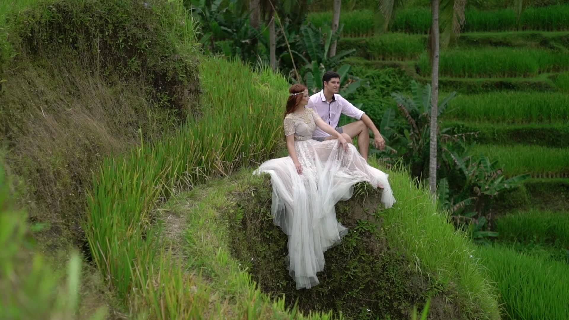 新婚夫妇坐在那里Bali在稻田台上手势手牵手拥抱浪漫视频的预览图