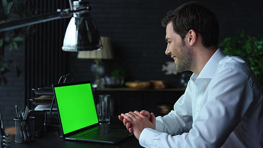 商人视频在办公室绿屏上用笔记本电脑在线聊天视频的预览图