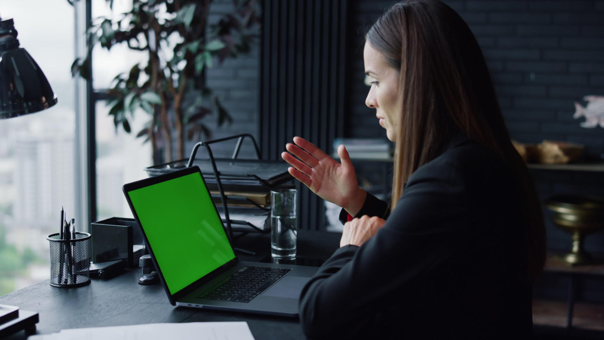 商业女性在办公室用绿屏笔记本电脑调用视频视频的预览图