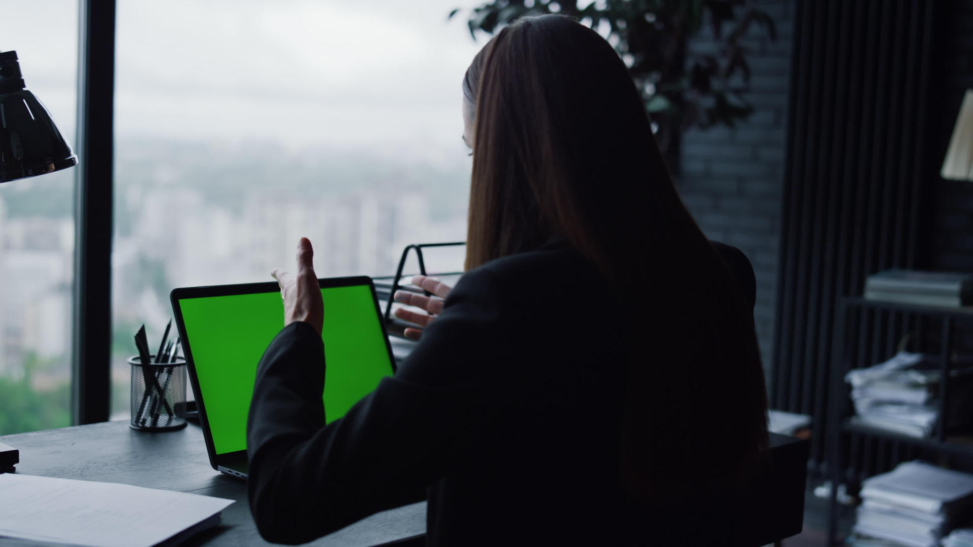 年轻女商人在家庭办公室使用带有绿色屏幕的笔记本电脑进行视频通话视频的预览图