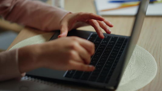 女孩在室内玩电脑键盘在笔记本电脑上学习视频的预览图