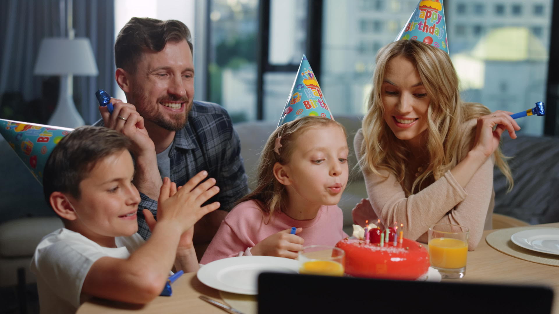 女孩和父母在蛋糕上吹蜡烛庆祝生日视频的预览图