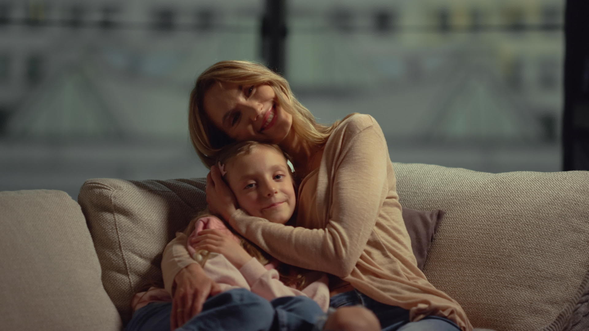 快乐的母亲和女儿拥抱在沙发上视频的预览图