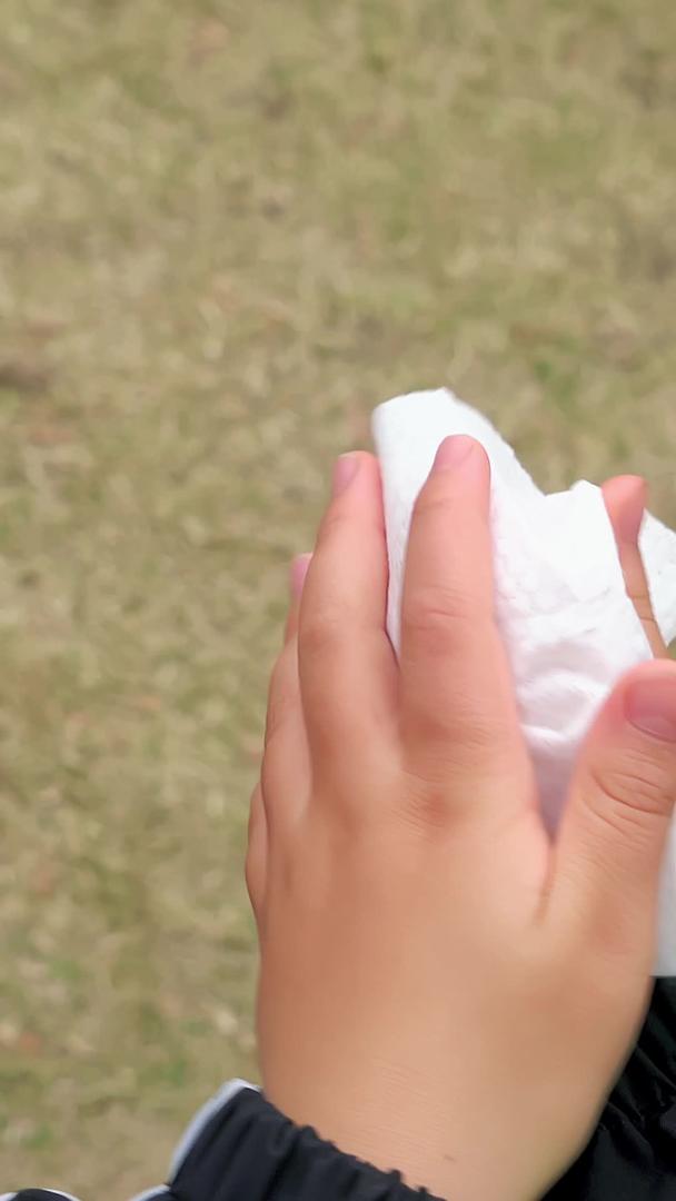 秋冬季节户外小男孩用纸巾擦手视频的预览图