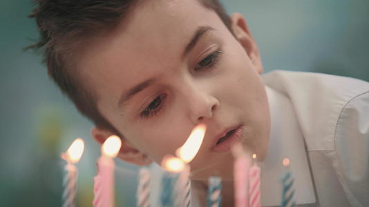 男孩在蛋糕上吹蜡烛火焰视频的预览图