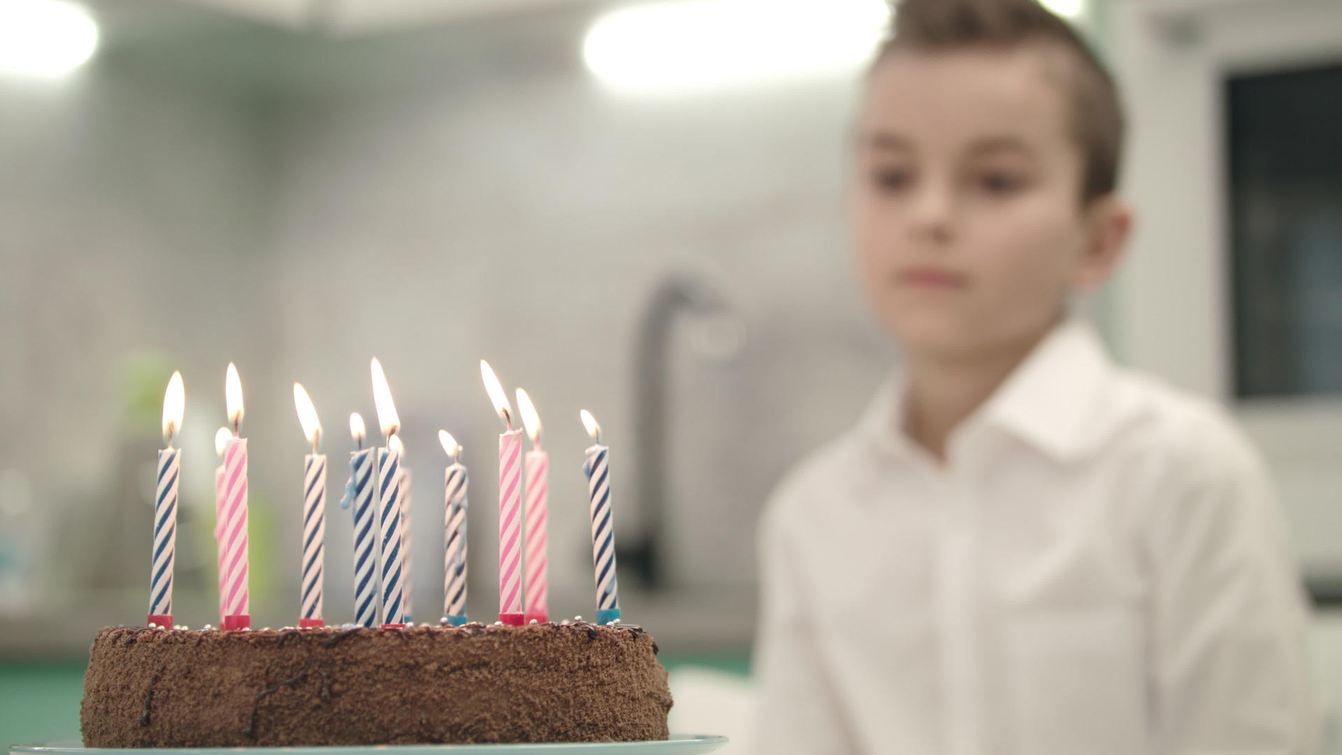 男孩正在看生日蛋糕蜡烛上的火焰视频的预览图