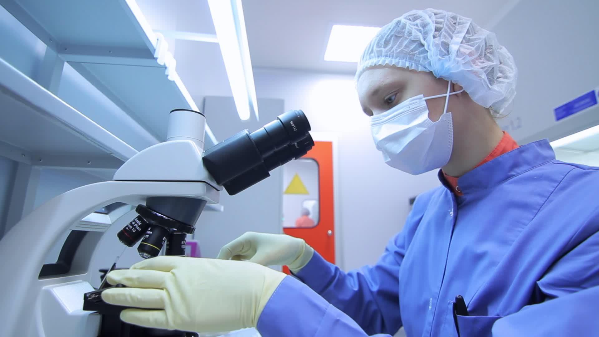 女性化学家在工厂化学实验室使用显微镜视频的预览图