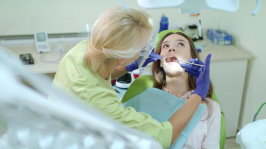 女性牙医使用口镜和注射器视频的预览图