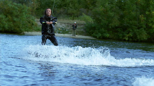 快乐的男人冲浪在船后湖上移动用手做标志视频的预览图