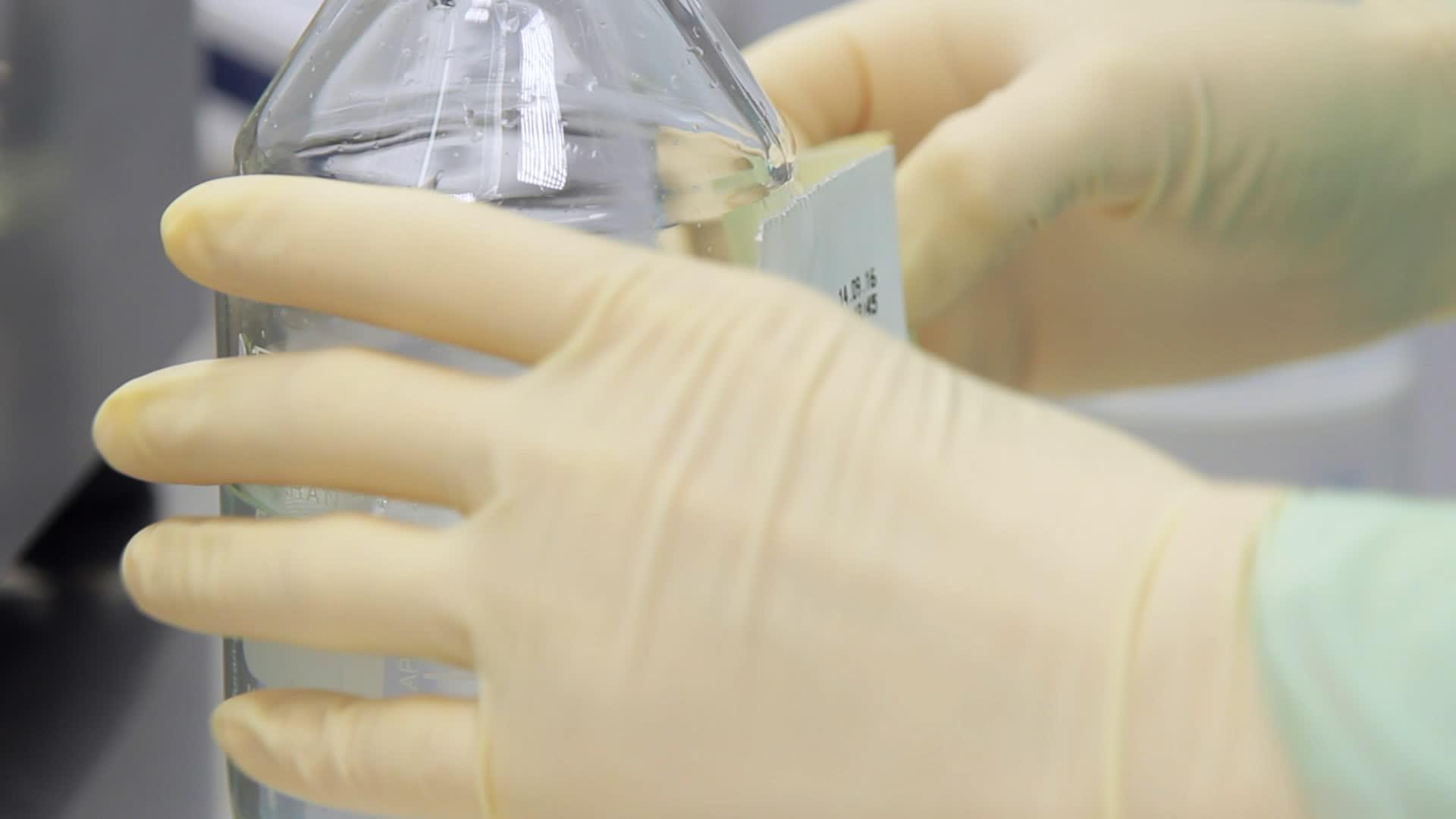 实验室工作人员在透明液体瓶上贴上标签视频的预览图