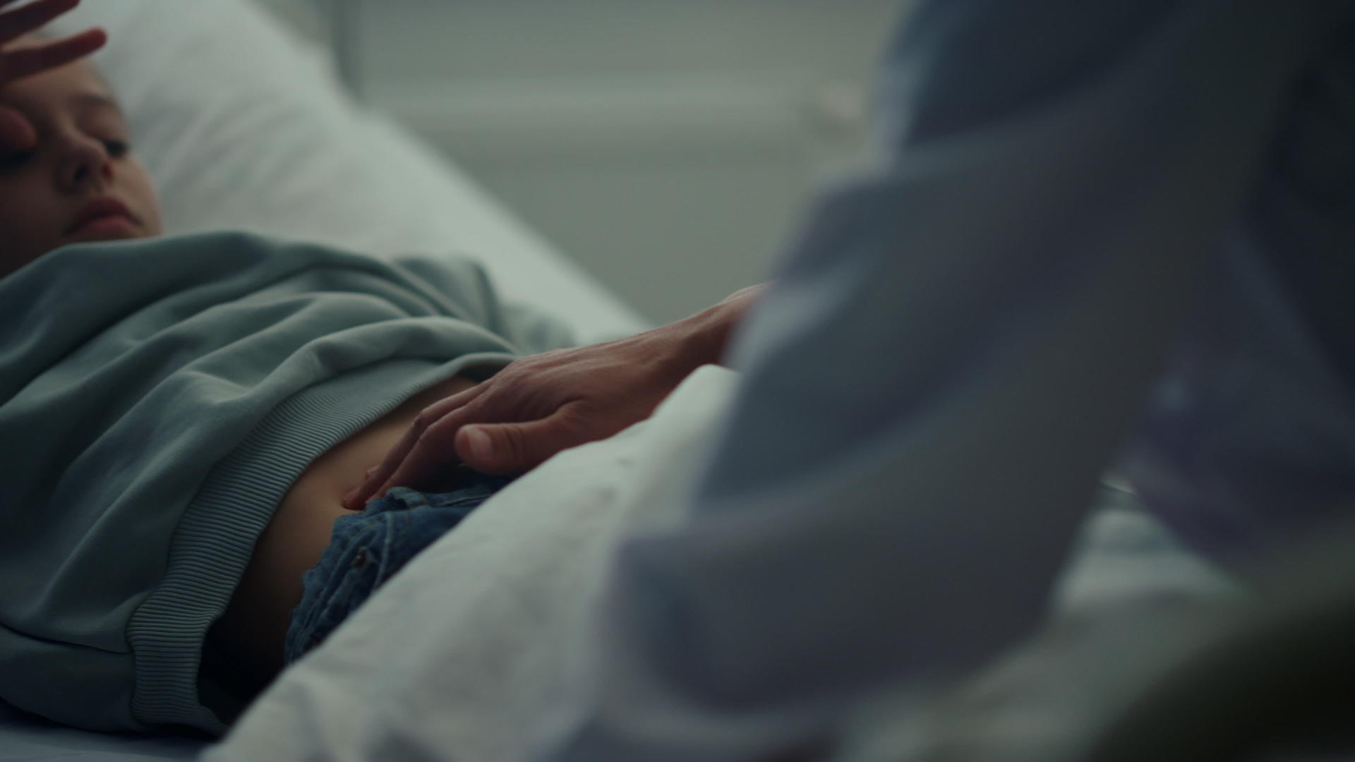生病的孩子躺在床上医生在急诊病房检查病人的胃视频的预览图